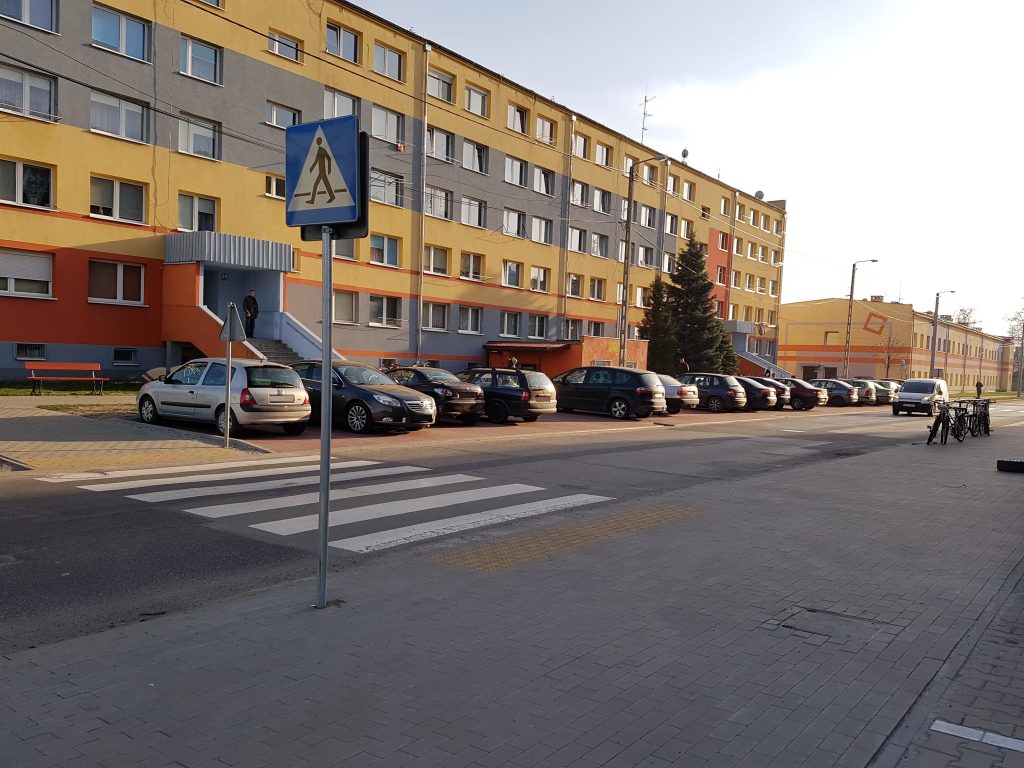 zdjęcie przedstawia uporządkowaną przestyrzeń publiczną - chodniki, ciąg pieszo-rowerowy, parking