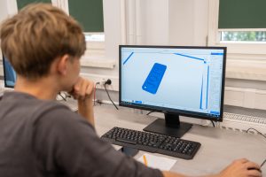 uczeń przy komputerze projektuje w programie typu CAD jakiś element