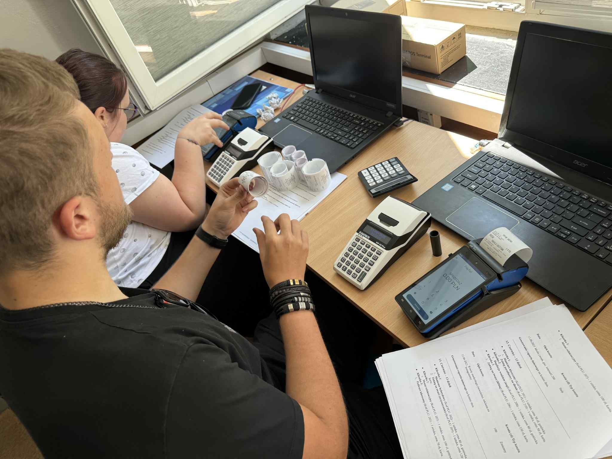 Dwie osoby pracujące przy komputerach w szkolnej sali komputerowej